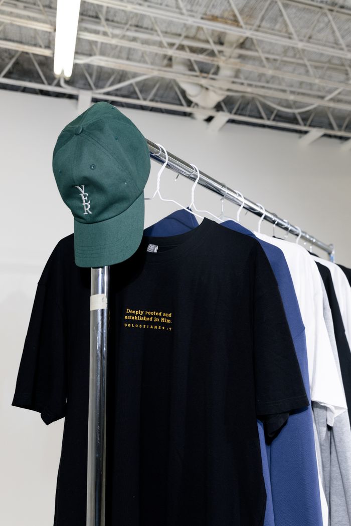 services-01 A variety of colorful T-shirts and a cap on a display rack in a modern store.