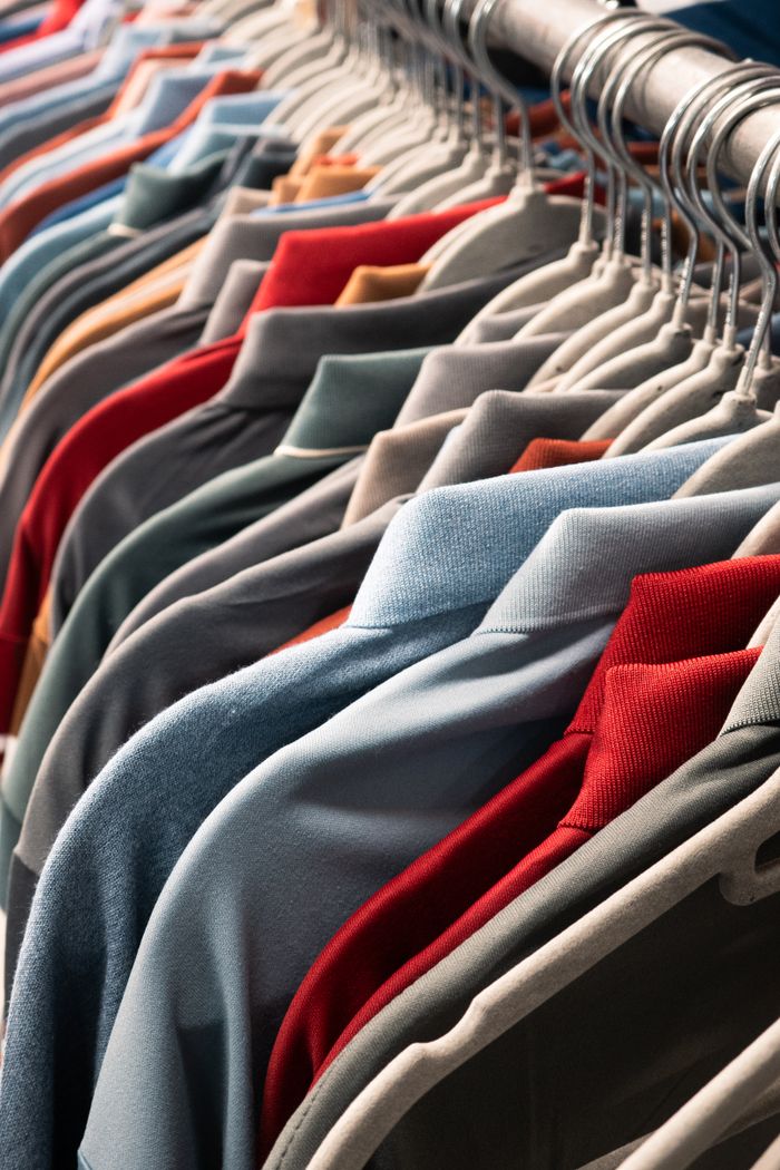 services-03 A vibrant row of various colored t-shirts neatly arranged on hangers in a store setting.