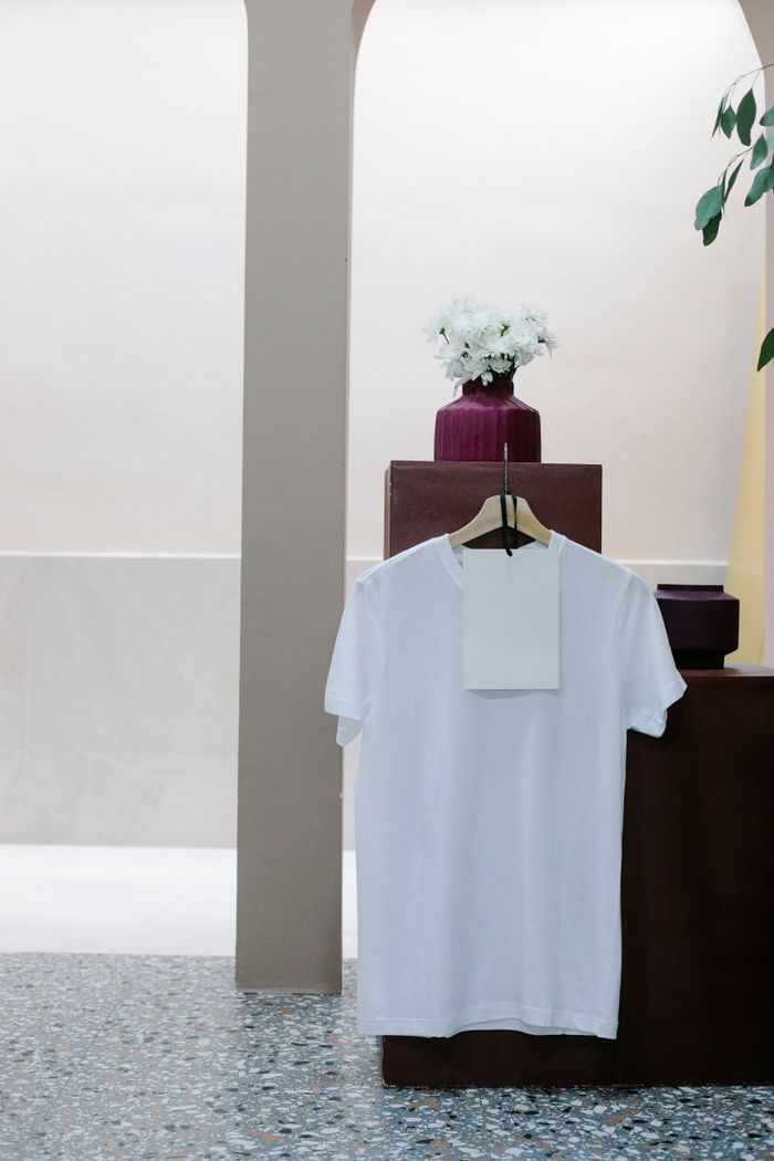 gallery-1 White t shirt with blank label hanging on counter in modern clothes shop
