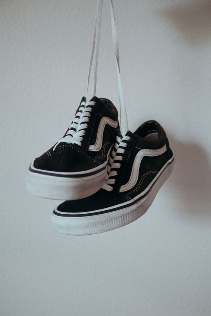 services-img Black sneakers with white shoelaces hanging on a wall.