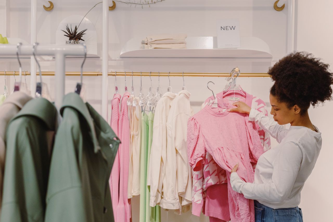gallery-2 A stylish woman explores pink and pastel outfits in a modern boutique.